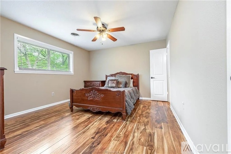 A bedroom with a bed, dresser, and window.