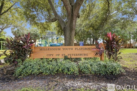 A sign for the Millennium Youth Playground in St. Petersburg is surrounded by greenery.