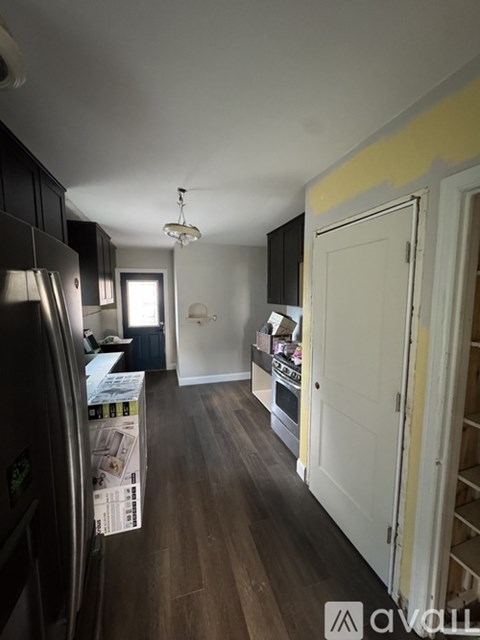 A kitchen with a refrigerator on the left and a wooden floor.