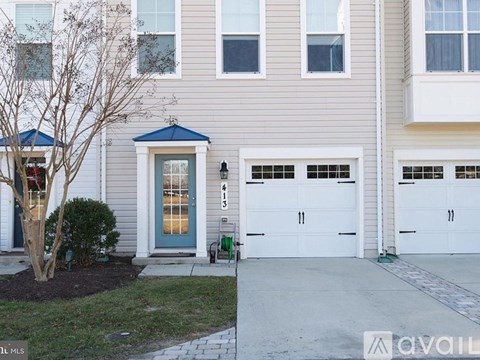 A two-story house with a blue door and white garage doors.