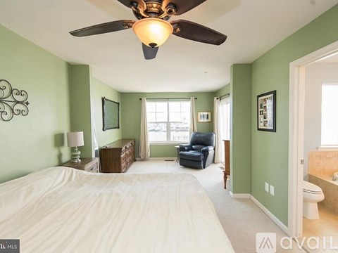 A bedroom with a bed, chair, and ceiling fan.
