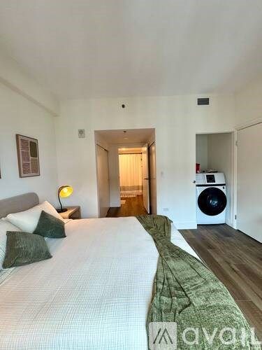 A bedroom with a large bed and a washing machine in the corner.