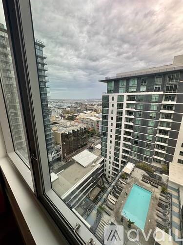 A view from a window looking out at a cityscape and a pool.