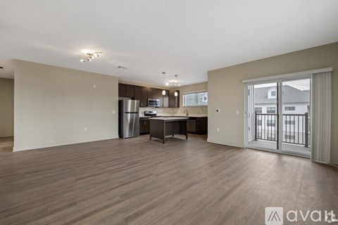 A spacious living room with a kitchenette in the background.