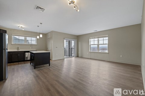 A spacious living room with wood flooring and a kitchen area with stainless steel appliances.