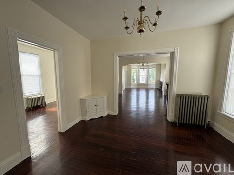 A large empty room with wooden floors and a chandelier.