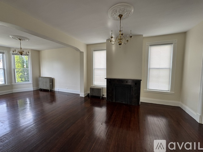 A large empty room with a fireplace and wood flooring.