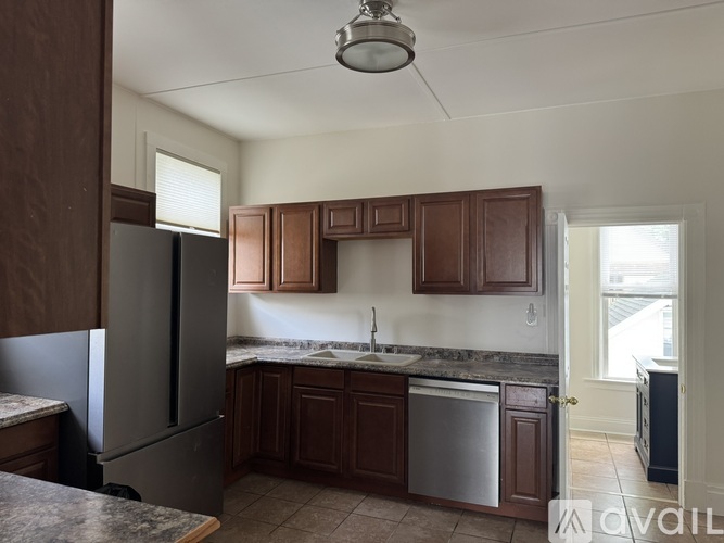 A kitchen with brown cabinets and a stainless steel refrigerator.