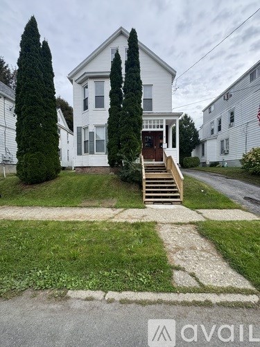 A white house with a brown door and steps leading to the entrance.