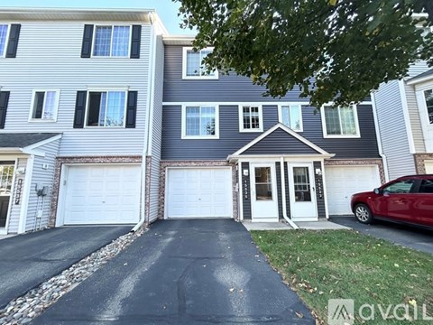 A two-story house with a red car parked in front.