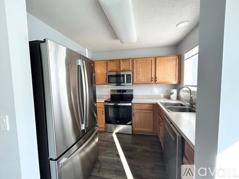 A kitchen with a stainless steel refrigerator and wooden cabinets.