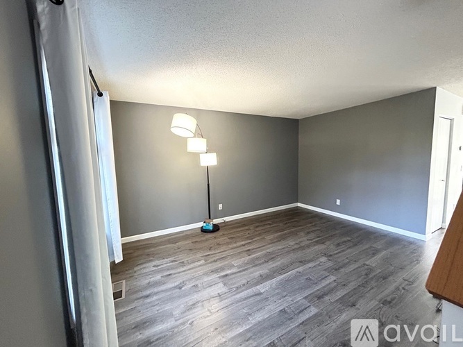 A room with grey walls and wooden flooring is available for rent.