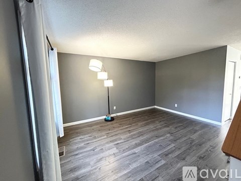 A room with grey walls and wooden flooring is available for rent.