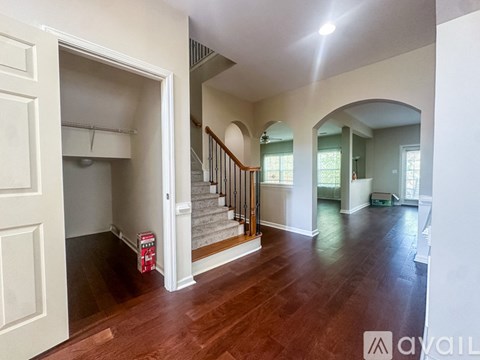A spacious room with wood flooring and a staircase leading to the upper level.