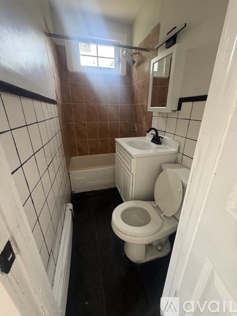 A bathroom with brown tiles and a white toilet.