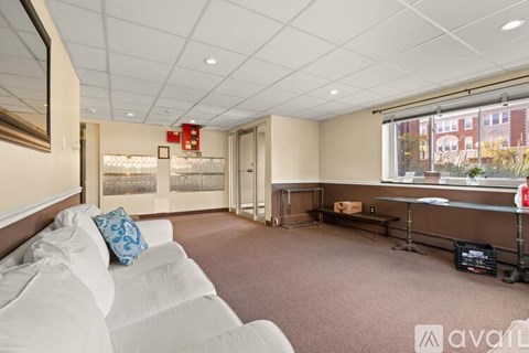 A living room with a white couch and a window with a view of a building outside.