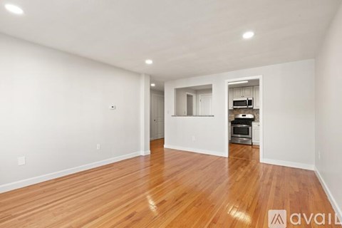 A spacious room with wooden flooring and white walls.