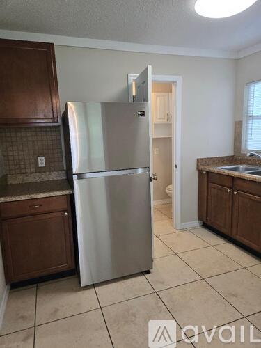 A kitchen with a stainless steel refrigerator and wooden cabinets.