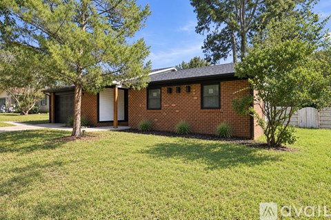 A house with a white door and windows is surrounded by greenery.