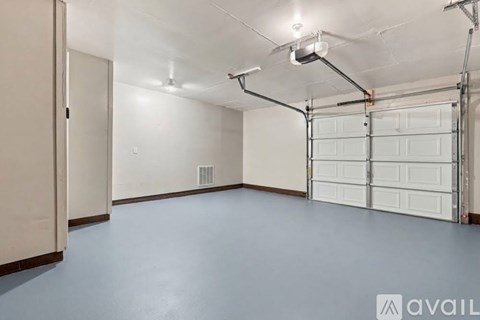 A spacious garage with a white door and a wall-mounted light fixture.