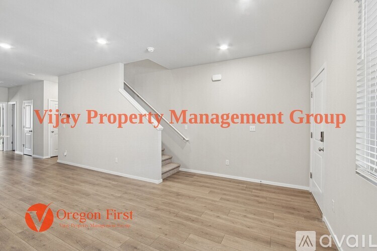 A spacious room with wood flooring and white walls, managed by Vijay Property Management Group.