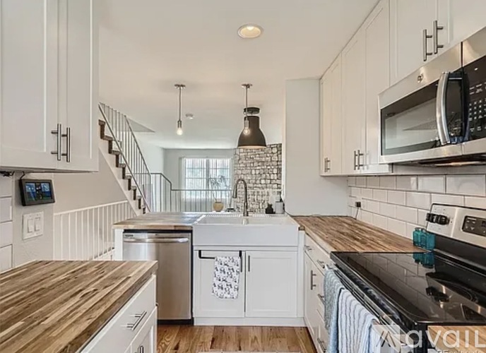 A kitchen with white cabinets and a wooden counter top.