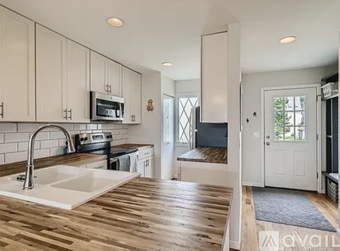 A kitchen with a white sink and wooden floors.