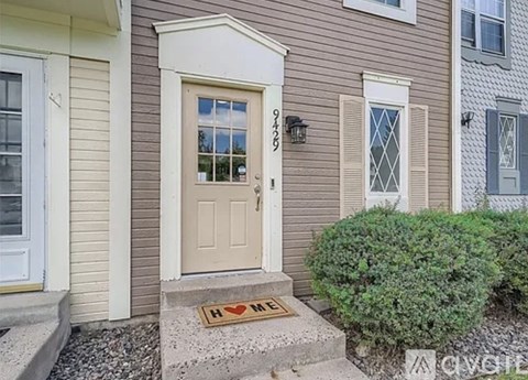 A house with a brown door and a doormat that says "H M".