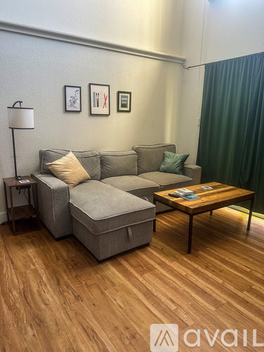 A living room with a grey couch, a wooden coffee table, and a lamp.