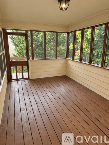 A room with wooden flooring and a window overlooking trees.