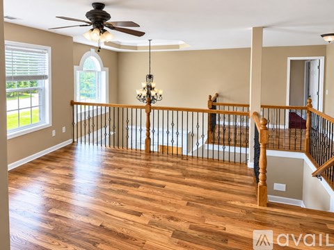 A living room with a wooden floor and a ceiling fan.