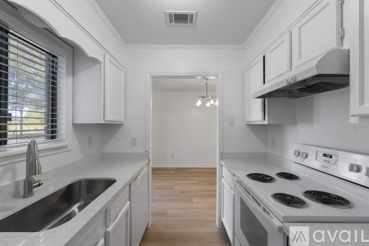 A kitchen with white cabinets and a stainless steel sink.