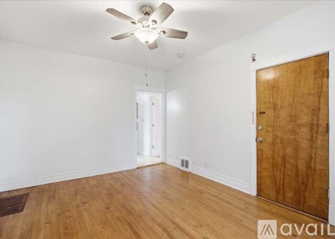 A room with a ceiling fan and wooden flooring.