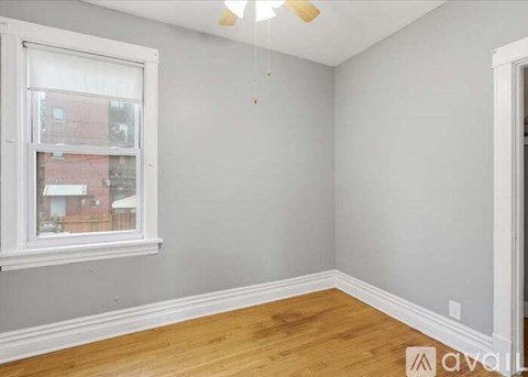 A room with wooden floors and a window overlooking a building.