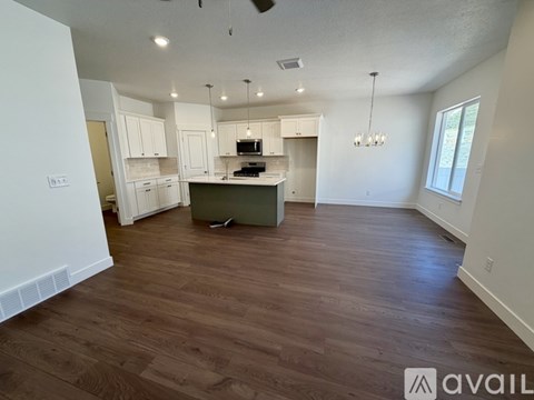 A spacious kitchen with wood flooring and white walls.