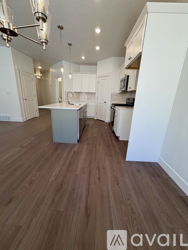 A kitchen with white cabinets and a wooden floor.