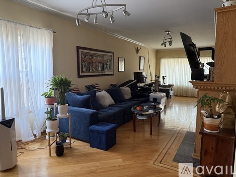 A living room with a blue couch and a wooden floor.
