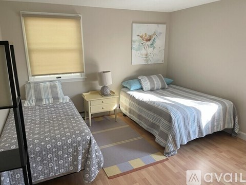 A bedroom with two beds, one with a grey patterned bedspread and the other with a blue striped bedspread.