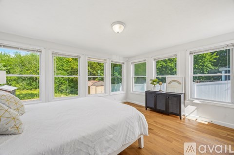 A bedroom with a large bed and a view of the backyard through the windows.