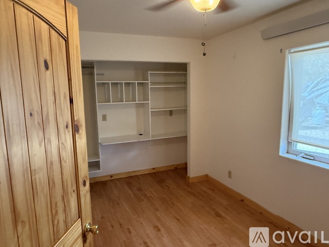 A room with a wooden floor and a white wall with a window.