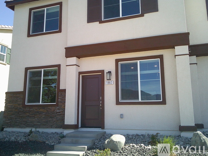 A beige house with a brown door and windows.