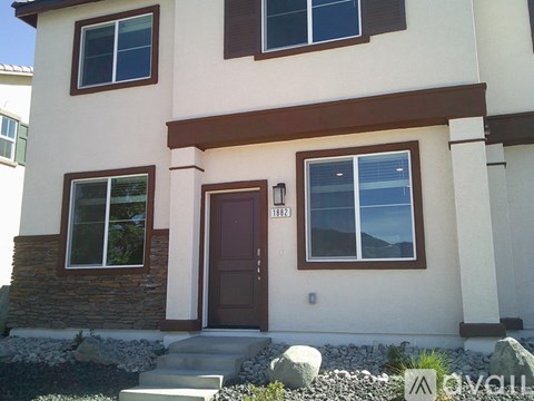 A beige house with a brown door and windows.