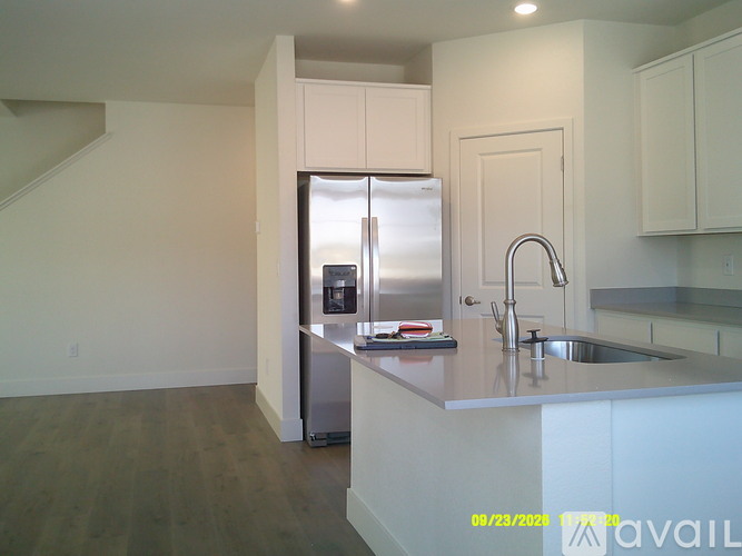 A kitchen with a refrigerator, sink, and cabinets.