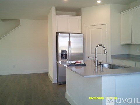 A kitchen with a refrigerator, sink, and cabinets.