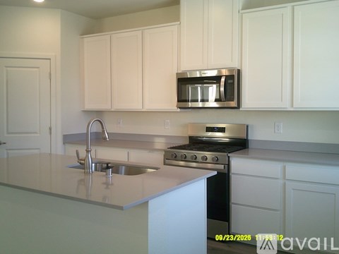 A kitchen with white cabinets and a stainless steel microwave above the stove.