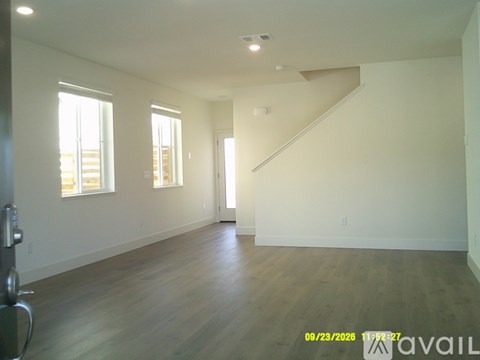 A spacious room with wooden floors and a staircase leading to another level.