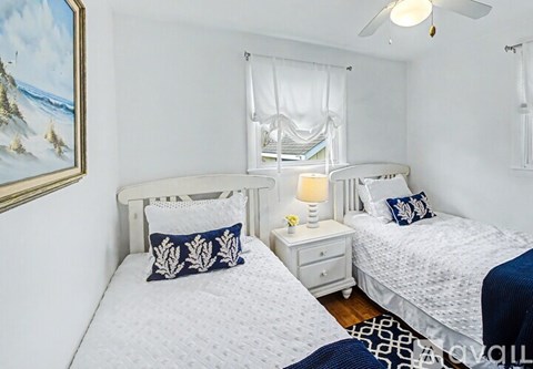 A bedroom with two beds, one with a white canopy, and a painting on the wall.
