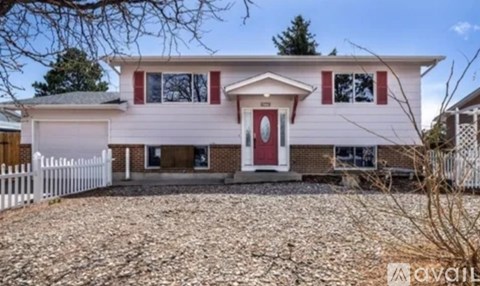 A white house with a red door and windows is for sale.