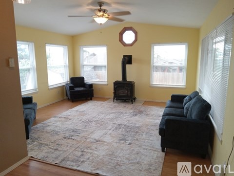 A living room with a rug, a fireplace, and a ceiling fan.