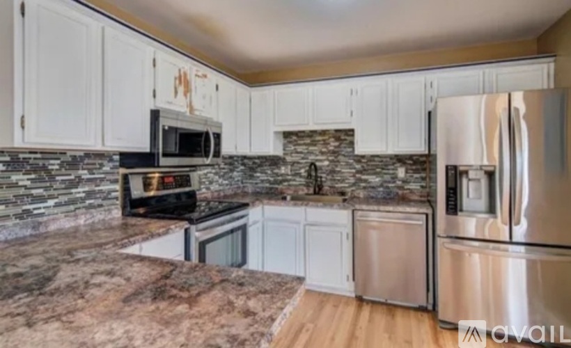 A kitchen with white cabinets and a stone backsplash.